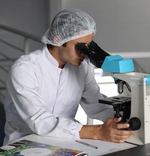 穿白大褂的学生调查显微镜