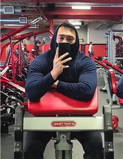 男人坐在健身器看着手机
